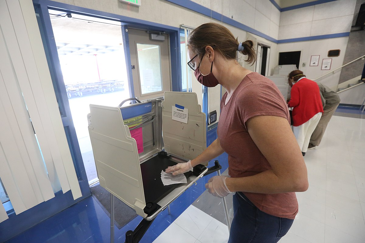 Poll worker sanitizes election booth